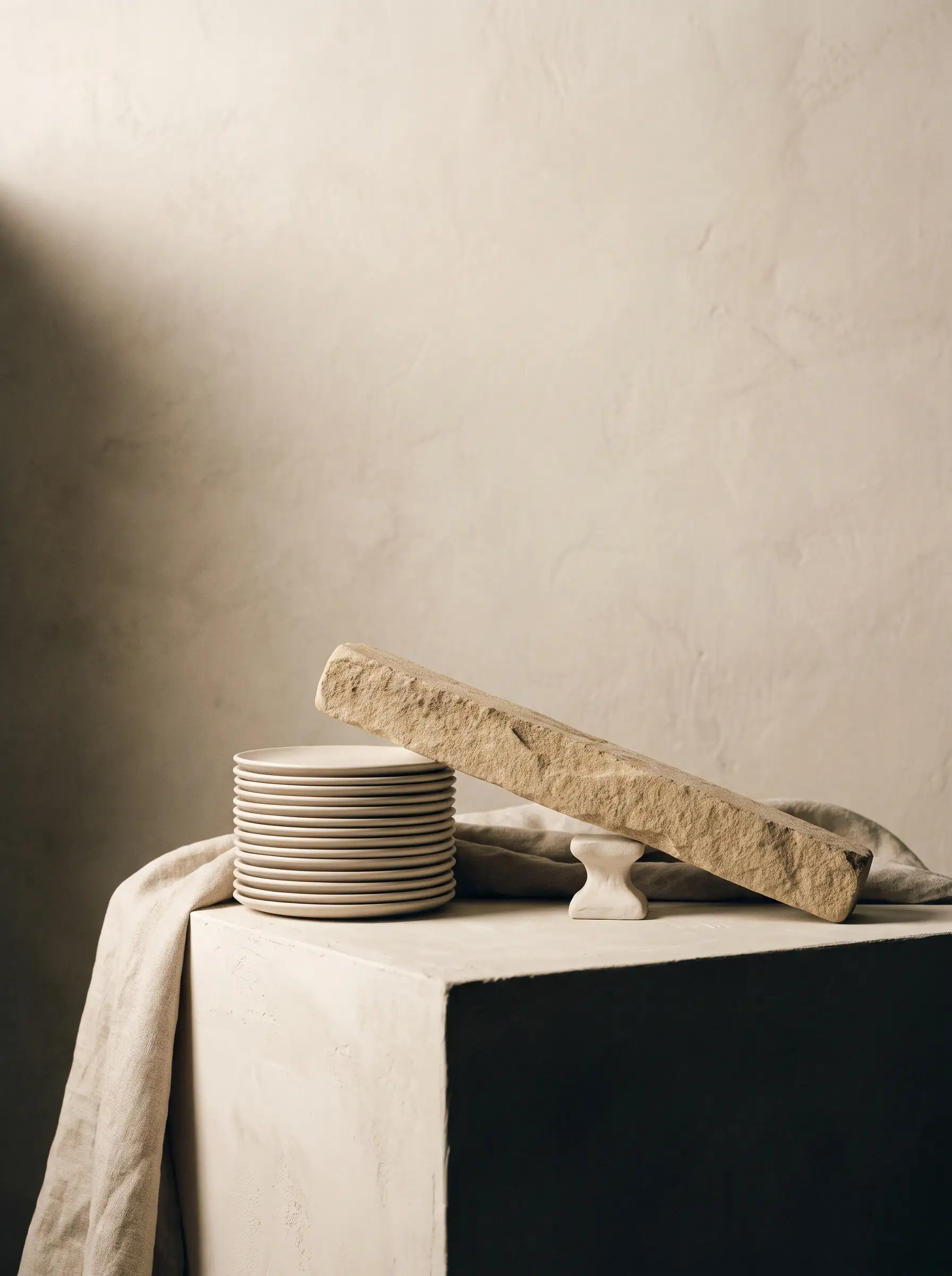 Editorial still-life for LASEO's Fintech SEO Agency page: a precise stack of thin pale ceramic discs beside a sandstone beam balanced on a fulcrum, on a plaster pedestal
