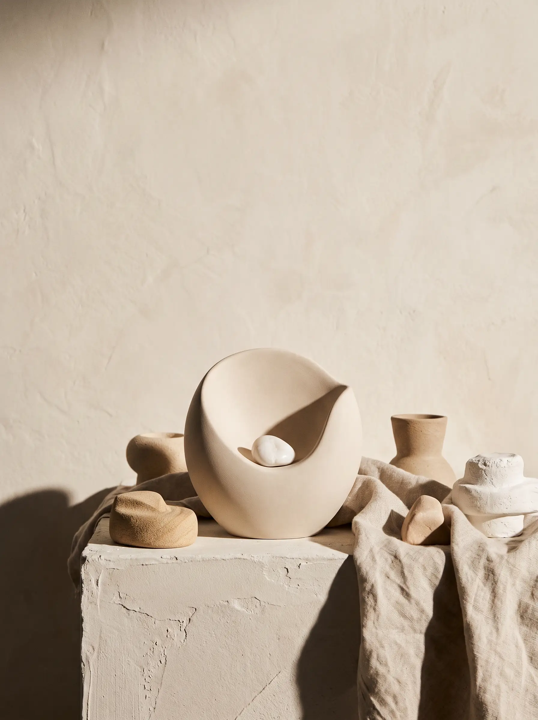 Editorial still-life voor LASEO's pagina SEO-bureau voor de zorg: een gladde, lichte keramische vorm met een beschermende welving die een kleine gepolijste witte steen omvat.